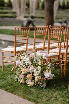 the chairs are lined up with flowers and greenery in front of them on the grass