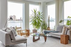 a living room filled with lots of furniture and large windows overlooking the water's edge