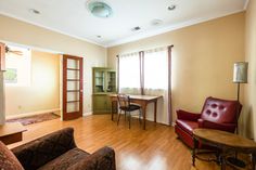 a living room filled with furniture next to a wooden table and two red leather chairs