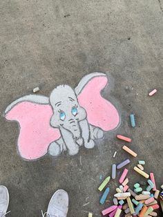 someone's feet are standing on the sidewalk with chalk crayons in front of them