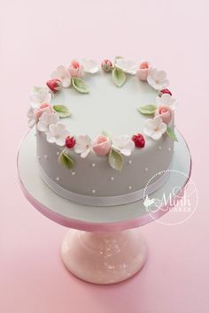 a white cake with pink flowers and green leaves