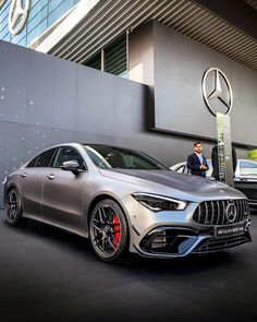 two mercedes cars are parked next to each other in front of a building with people looking at them