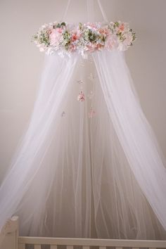 a white canopy with flowers hanging from it's side in a baby crib