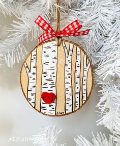 a wooden ornament hanging from a christmas tree decorated with red and white plaid ribbon