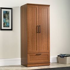 a tall wooden armoire next to a wall with pictures on the wall behind it