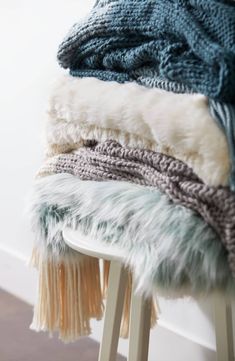 a stack of blankets sitting on top of a wooden stool