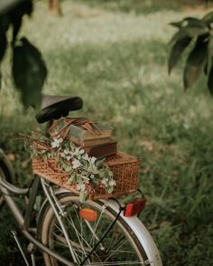 an old bicycle with flowers and books on the front basket is parked under a tree