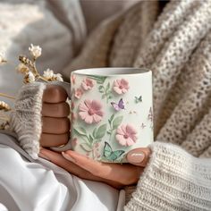 a woman holding a coffee mug with pink flowers on it