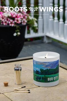 a white candle sitting on top of a table next to some sticks and a cup