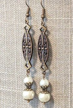 Gorgeous handcrafted vintage style earrings, perfect for a bride!! Created using antique brass links with Art Nouveau and Art Deco motifs, ear wires and intricate filigree bead caps and two sizes of lustrous, creamy ivory glass pearls!!  Length 3" Victorian Chandelier Earrings With Intricate Design, Victorian Chandelier Dangle Earrings With Intricate Design, Antique Bronze Earrings For Wedding, Antique Filigree Dangle Chandelier Earrings, Antique Filigree Chandelier Dangle Earrings, Antique Gold Filigree Earrings, Ornate Antique Finish Dangle Earrings, Victorian Style Silver Earrings With Antique Finish, Vintage Silver Brass Chandelier Earrings