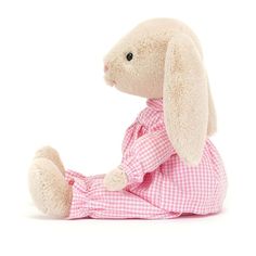 a stuffed rabbit in a pink dress sitting on the ground with its legs spread out