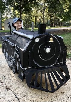 a young boy riding on top of a black train