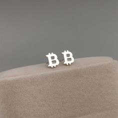 "Celebrate the world of cryptocurrency with our Bitcoin Stud Earrings. Handcrafted with sterling silver, these earrings capture the iconic Bitcoin symbol in a sleek and stylish design. Showcasing the distinctive \"B\" logo, these studs are a perfect accessory for cryptocurrency enthusiasts and tech-savvy individuals. Available in both sterling silver and gold plated, you can choose the finish that suits your personal style. These earrings are meticulously crafted to ensure durability and lasting shine. With their versatile design, they can be worn as a statement piece or as part of a trendy everyday look. Embrace the spirit of innovation and financial technology with our handmade Bitcoin Stud Earrings. Whether you're a Bitcoin investor or simply appreciate its significance, these earrings Financial Technology, B Logo, Tech Savvy, Earrings Sterling Silver, Sterling Silver Earrings Studs, Silver And Gold, Jewelry Earrings Studs, Satin Finish, Stylish Design