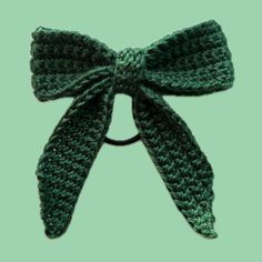 a crocheted bow is shown on a green background