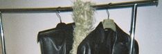 a black jacket hanging on a rack with some hair sticking out of it's back