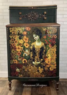 an ornate painted chest with flowers and a woman's face on the front, sitting against a white brick wall