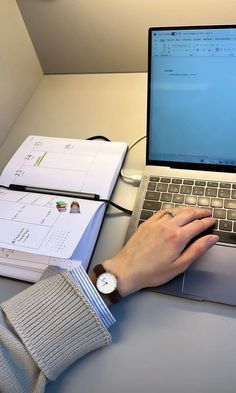 a person using a laptop computer on top of a desk next to several binders