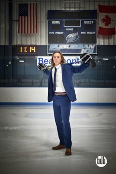 a man in a suit and tie standing on an ice rink with his hands up