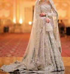 a woman in a wedding dress standing on the floor with her veil draped over her head