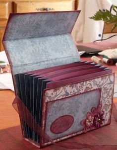 an open box sitting on top of a table next to a vase with flowers in it