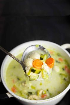 a spoon full of soup with cauliflower, carrots and celery