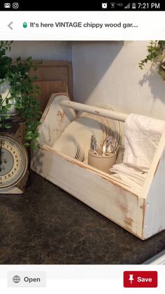 an old wooden box filled with dishes on top of a counter next to a clock