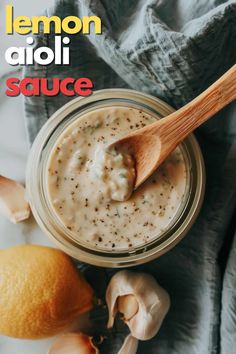 lemon aioli sauce in a glass jar with a wooden spoon and garlic on the side