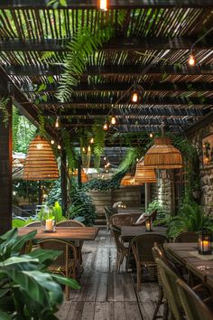 an outdoor dining area with wooden tables and wicker chairs, surrounded by greenery