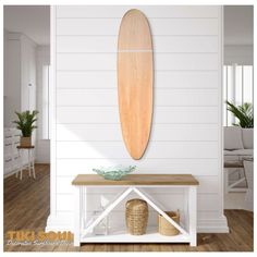 a wooden surfboard mounted on the wall above a table in a room with white walls