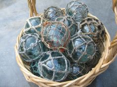 a basket filled with blue glass balls on top of a cement floor next to a wall