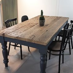 a wooden table with chairs around it and a cactus in the center on one side