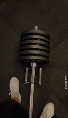 a person standing next to a black and silver dumbble weight machine on the ground