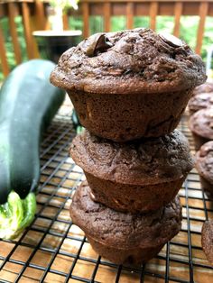 a stack of chocolate muffins sitting on top of a cooling rack next to an eggplant