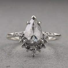 a pear shaped diamond ring set in 18k white gold with diamonds around the band