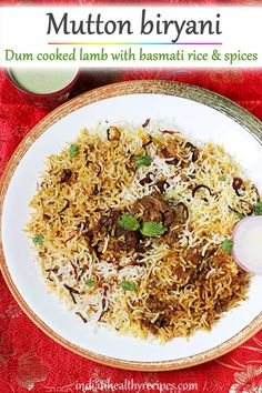 a white plate topped with rice and meat on top of a red tablecloth covered table