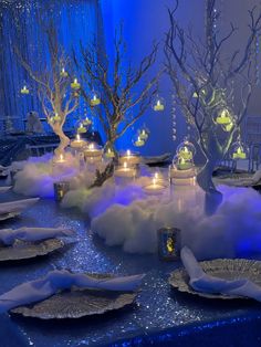 a table set up with candles, plates and trees in the middle of it covered in snow