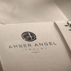 the logo for amber angel jewelry is displayed on two folded cards, both with black and white designs