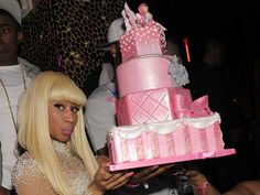 a blonde woman holding a pink cake with white icing on it's face