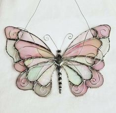 a pink and white butterfly hanging on a wall