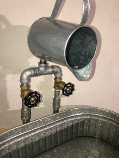 a metal bucket with two spigots attached to it