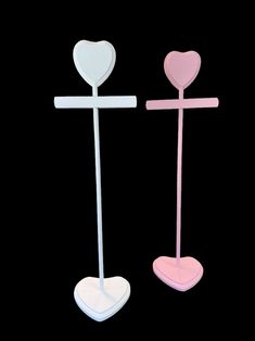 two pink and white crosses with hearts on them are standing side by side against a black background