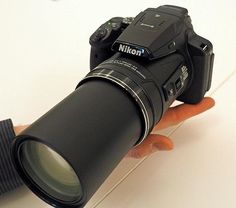 a hand holding a camera with a lens attached to it's body and the lens pointed up