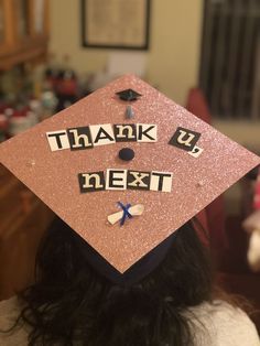 a person wearing a pink graduation cap with the words thank you next written on it