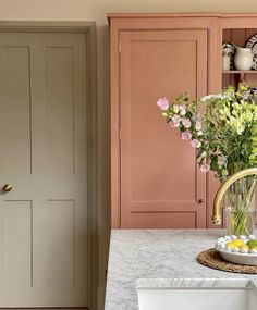 a vase filled with flowers sitting on top of a kitchen counter next to a door