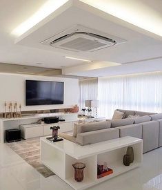 a living room with white furniture and a flat screen tv mounted on the wall above it