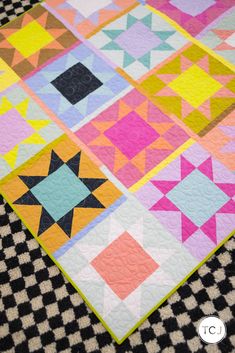 a colorful quilt is laying on top of a black and white checkered table cloth