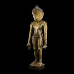 a gold colored statue is standing on a black background and it appears to be in the shape of a human