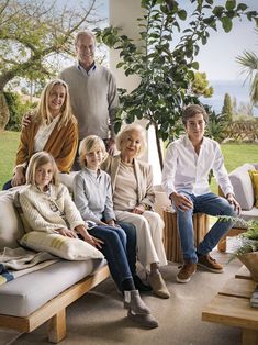 a group of people sitting on top of a couch in front of a green tree