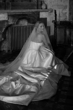 a woman in a wedding dress is sitting on the floor with her veil over her head