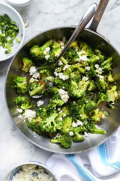 a pan filled with broccoli and feta cheese on top of a table